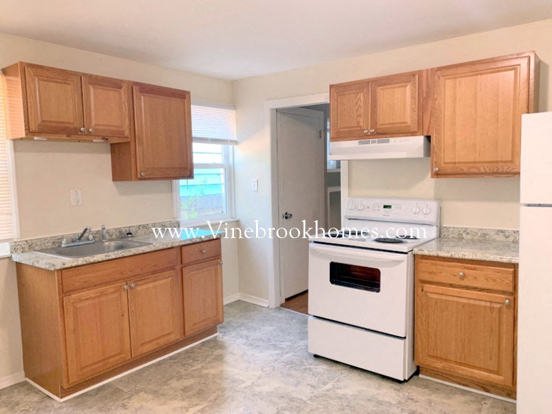 an empty kitchen with wooden cabinets and white appliances