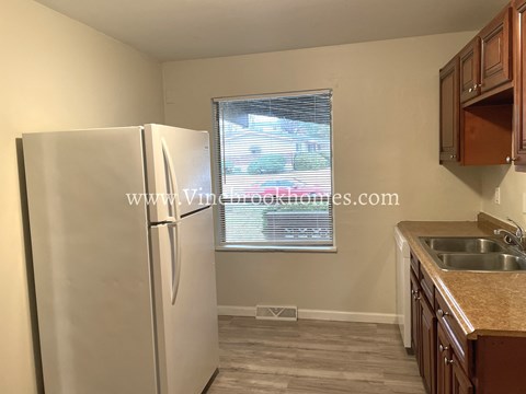 A kitchen with a white refrigerator and wooden cabinets.
