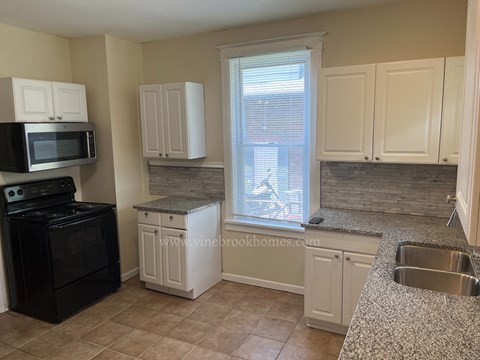a kitchen with white cabinets and a sink and a window