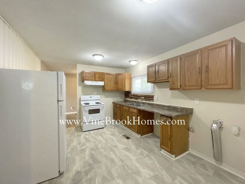 a kitchen with wooden cabinets and a refrigerator and a sink