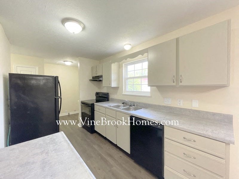 a kitchen with white cabinets and a black refrigerator and a sink