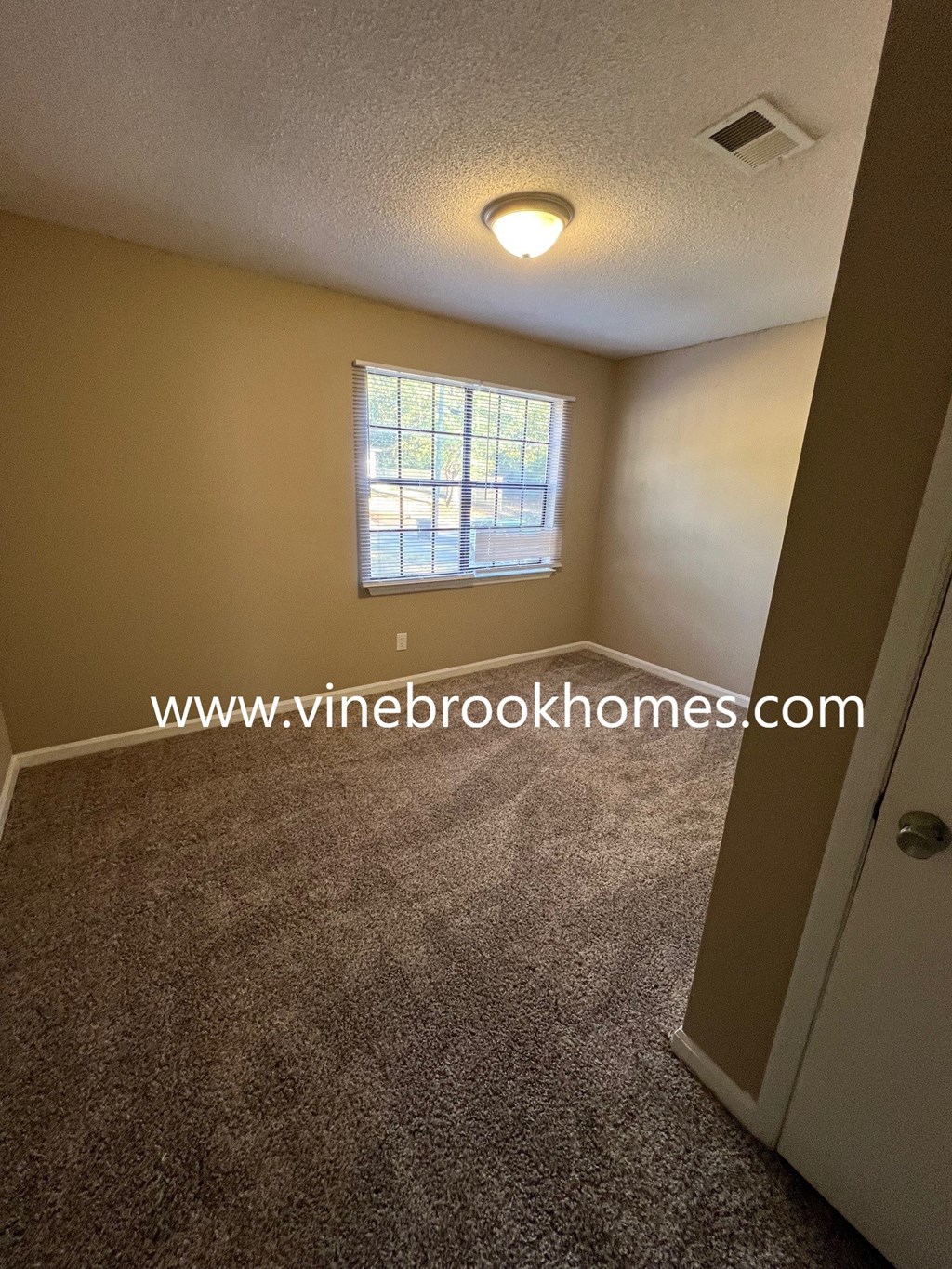 a small room with carpet and a window