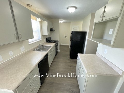 a kitchen with white cabinets and a black refrigerator and sink