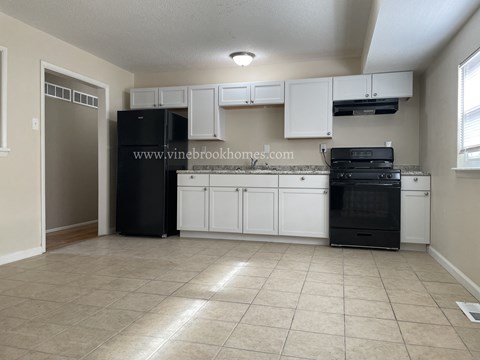 A kitchen with black appliances and white cabinets.