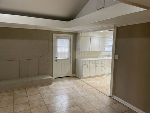 an empty kitchen with white cabinets and a door