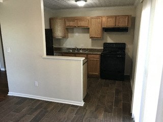 A kitchen with wooden cabinets and a black oven.