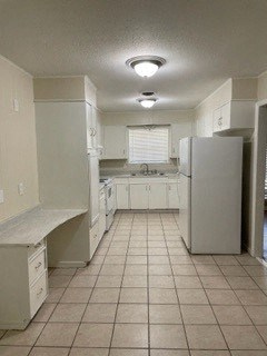 a white kitchen with a refrigerator and a sink