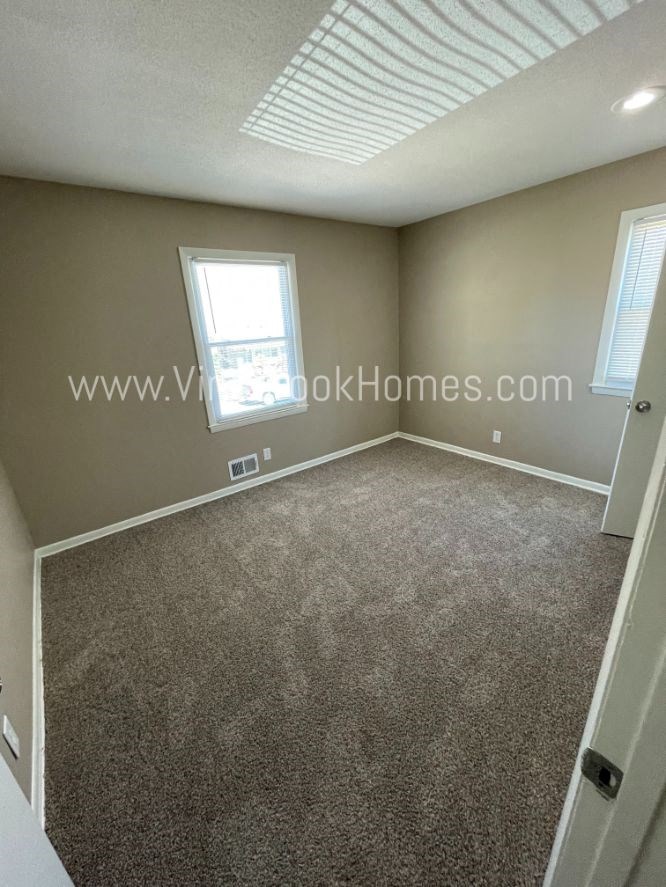 a large empty room with carpet and a window
