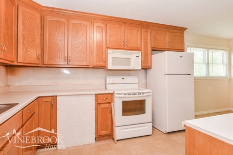 a kitchen with wooden cabinets and white appliances and a refrigerator