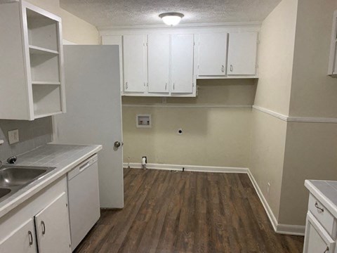 A kitchen with white cabinets and a wooden floor.