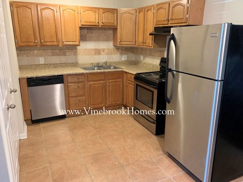 A kitchen with wooden cabinets and a black refrigerator.