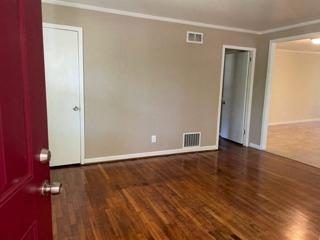 an empty living room with wood floors and a red door