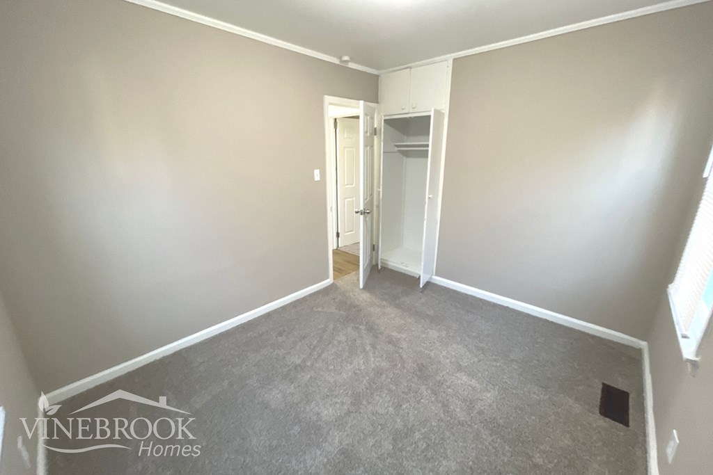 a bedroom with a carpeted floor and a door to a closet