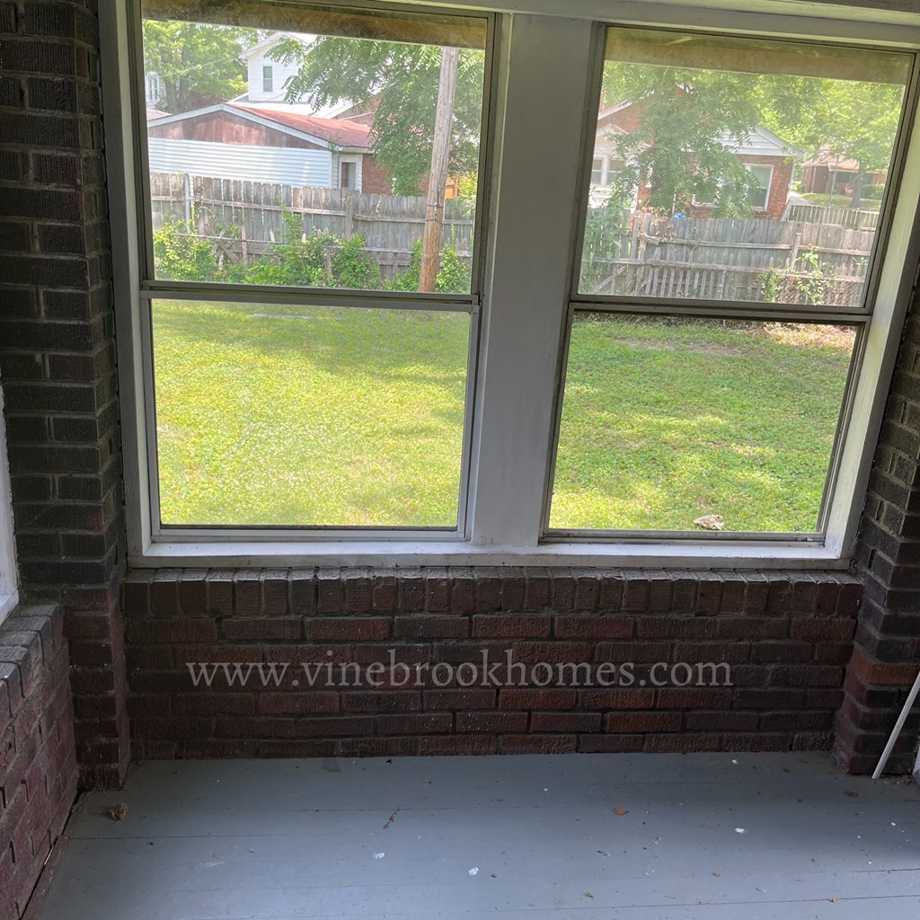 the view of a backyard from a window of a brick house