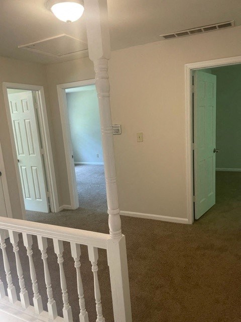 a hallway with a white staircase and a green door