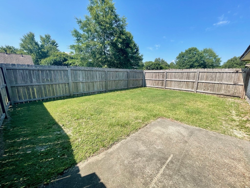 a backyard with a wooden fence and grass