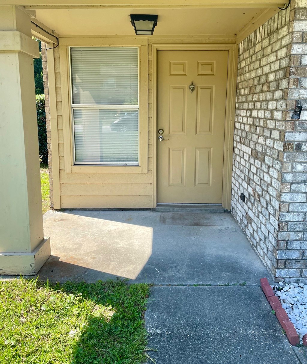 a front porch of a brick house with a yellow door