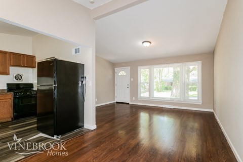 A black fridge in a kitchen with wooden cabinets and a stove.