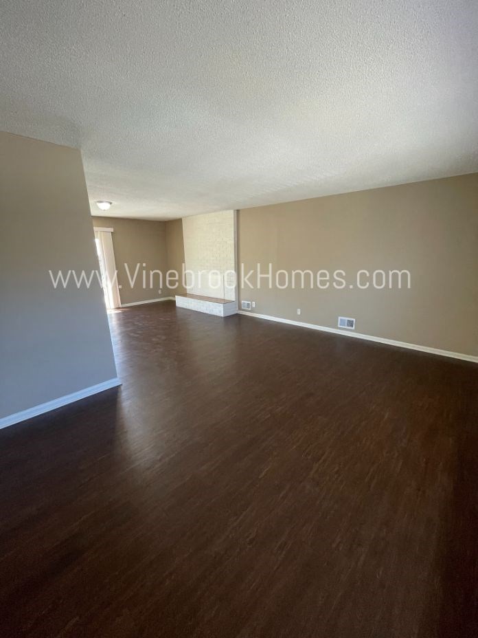 an empty living room with wood floors and white walls