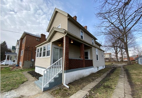 A two-story house with a red brick exterior and a white front porch.