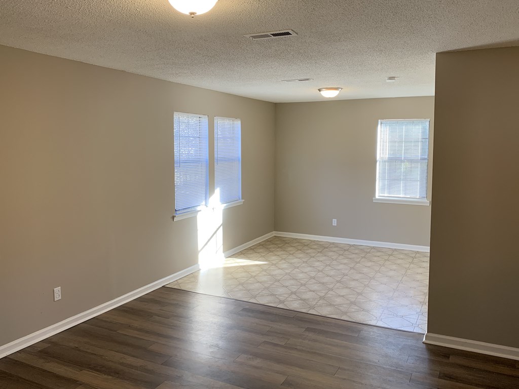 an empty living room with wood floors and a window