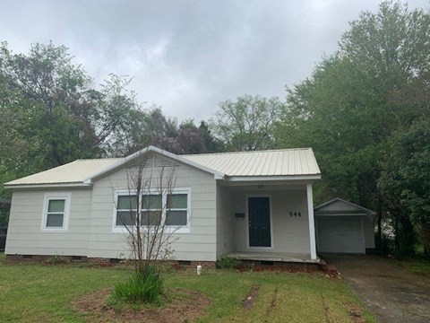 a small white house with a yard and trees