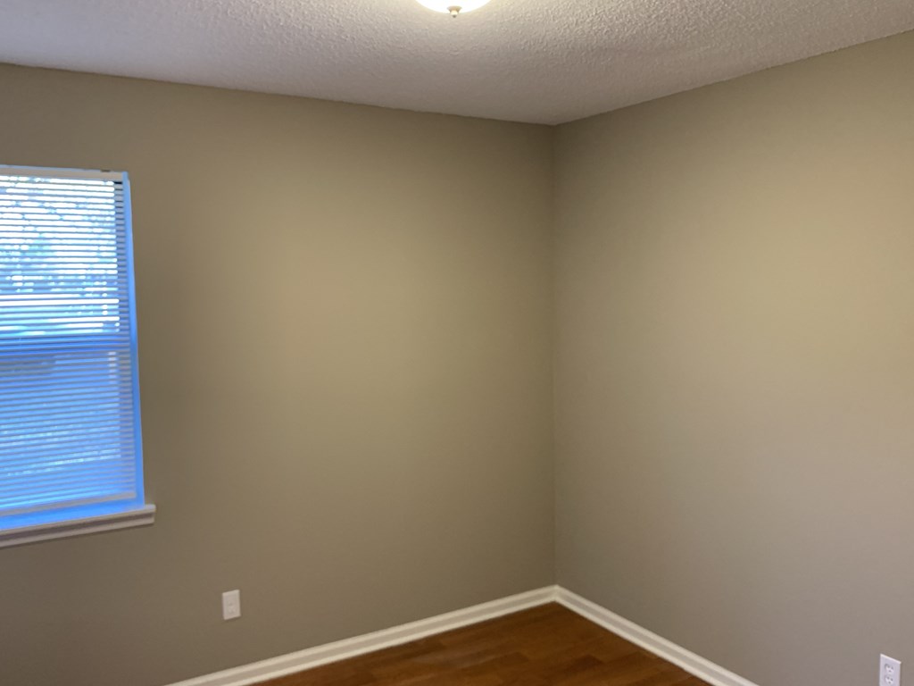 the corner of a room with a window and wooden floors
