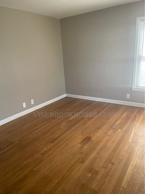 a living room with a wooden floor and grey walls