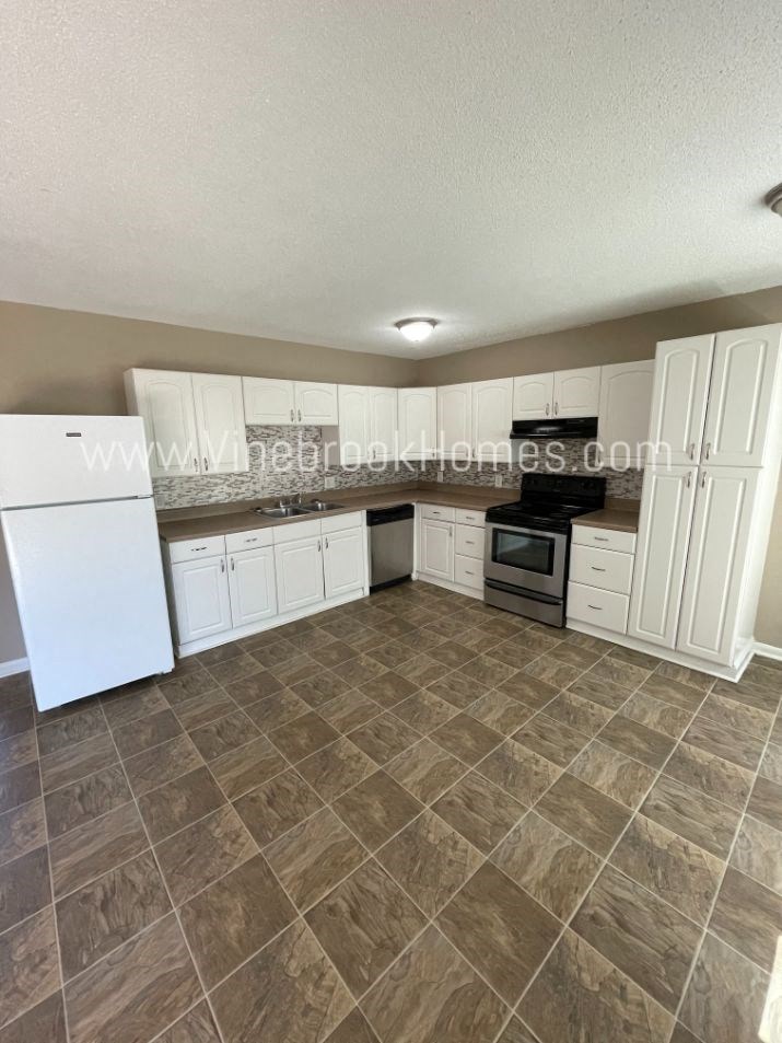 a kitchen with white cabinets and tile floor