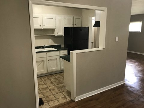 A kitchen with white cabinets and a black fridge is shown.
