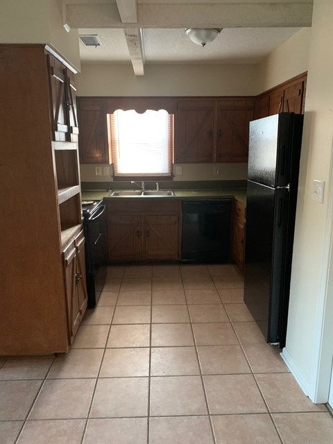 A kitchen with black appliances and brown cabinets.