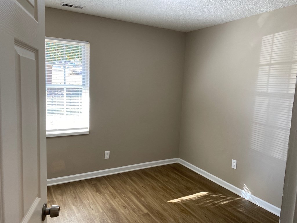 an empty room with wood floors and a window