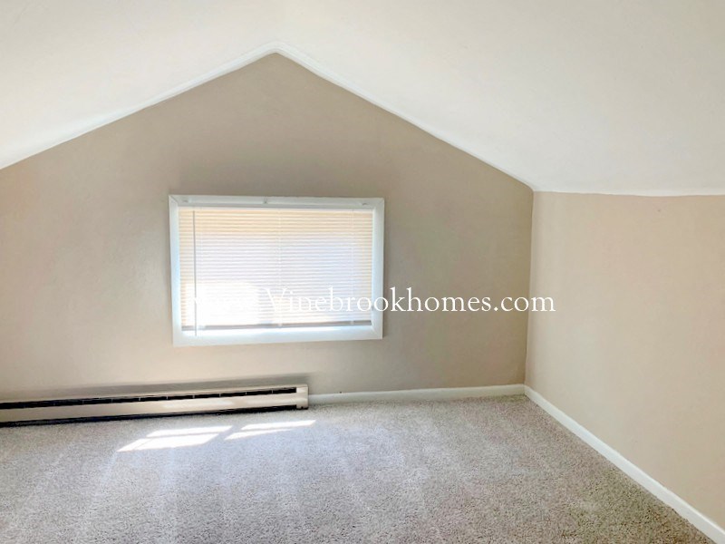 a small bedroom with a window and a carpeted floor