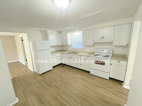 A kitchen with white appliances and cabinets.