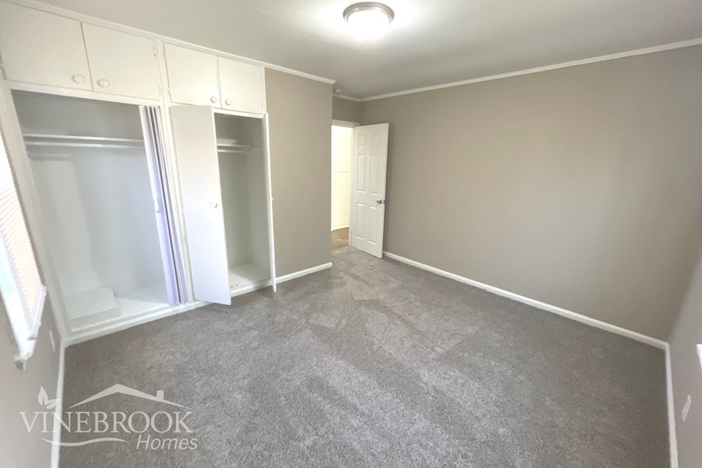 a bedroom with a carpeted floor and a closet with a mirrored door