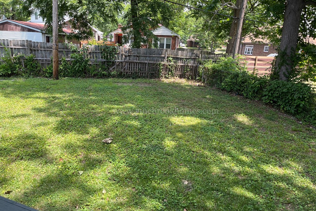 a backyard with a fence and a yard with green grass