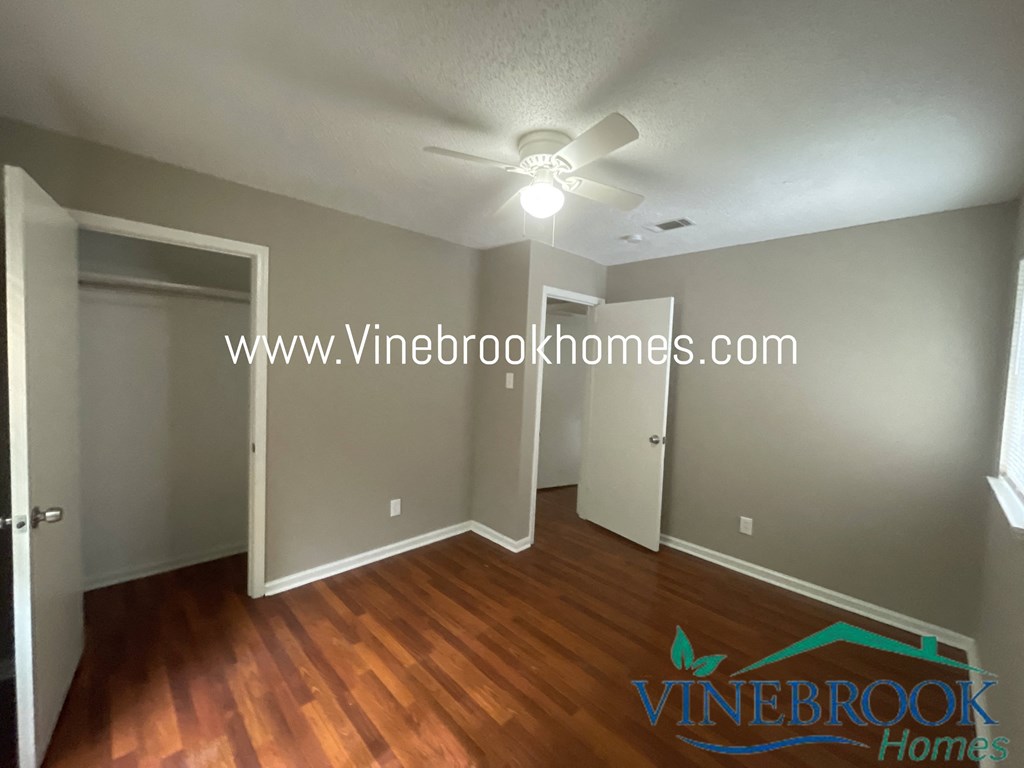 a bedroom with a wood floor and a ceiling fan