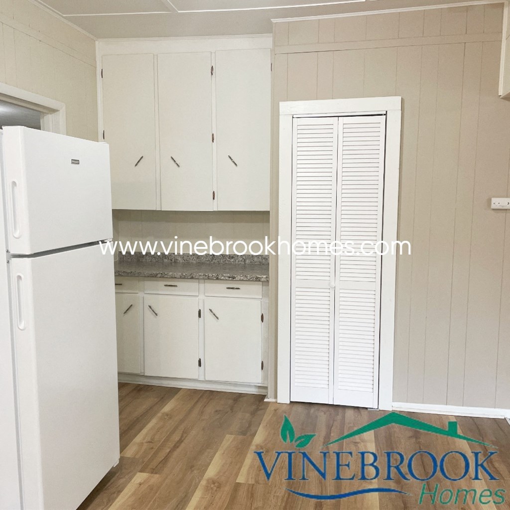 a small kitchen with white cabinets and a refrigerator