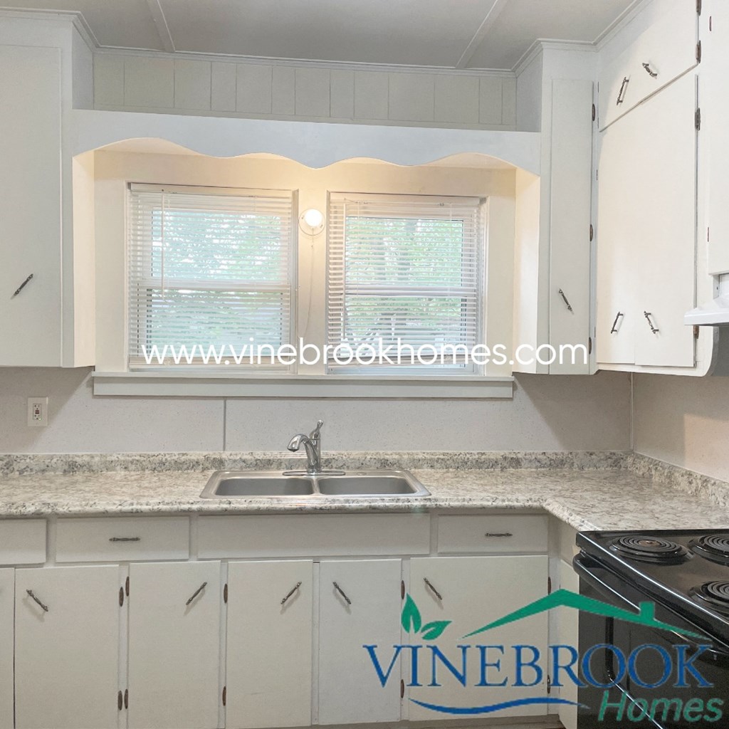 a kitchen with white cabinets and a sink and a window