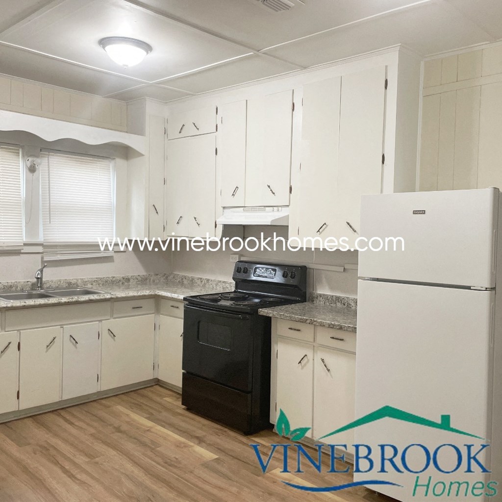 a renovated kitchen with white cabinets and black appliances