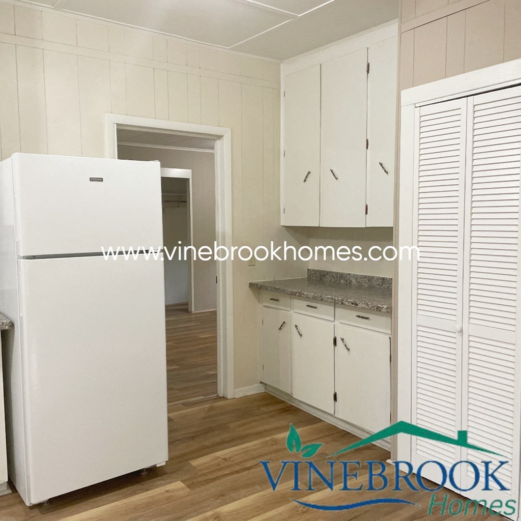a small kitchen with white cabinets and a refrigerator