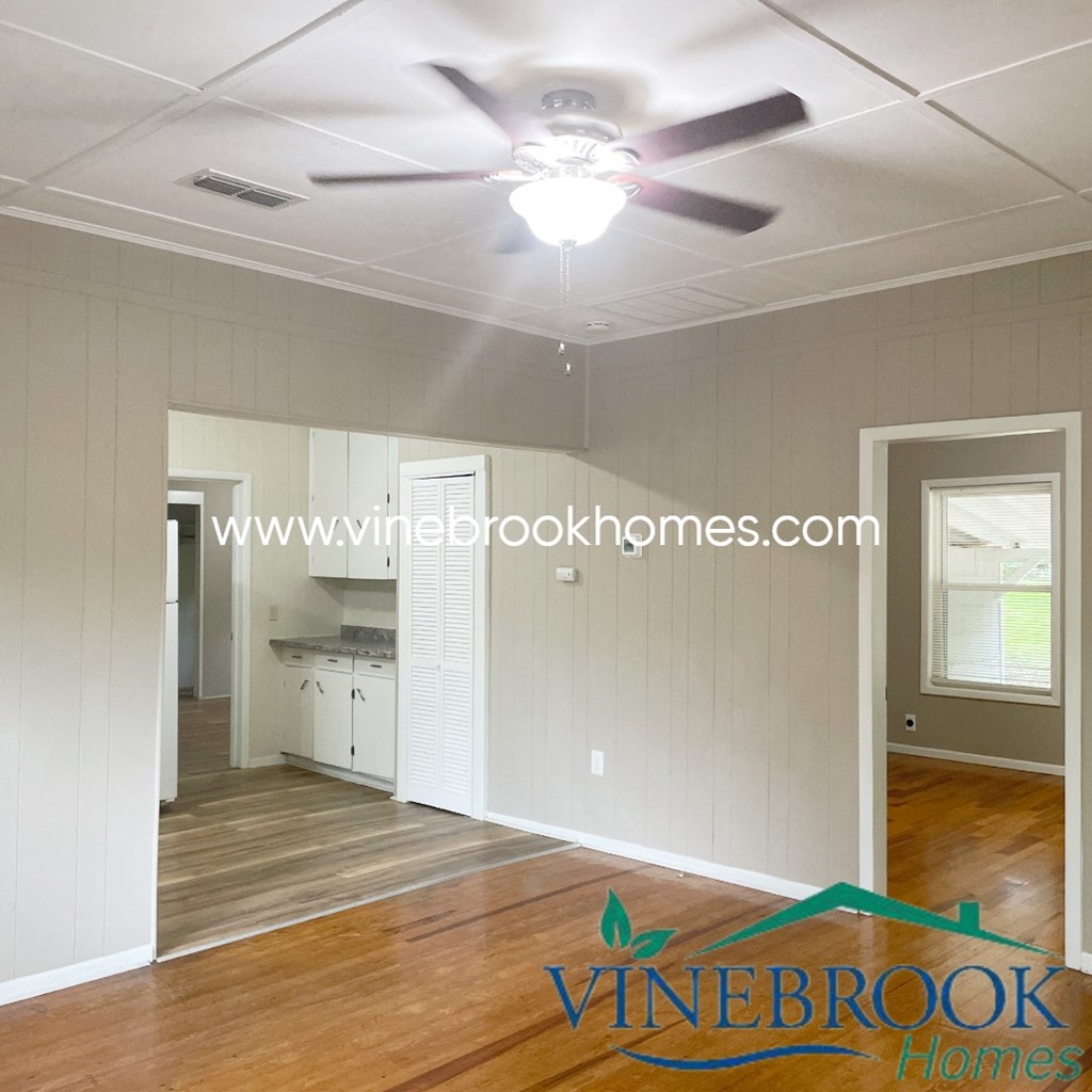 an empty living room and kitchen with a ceiling fan