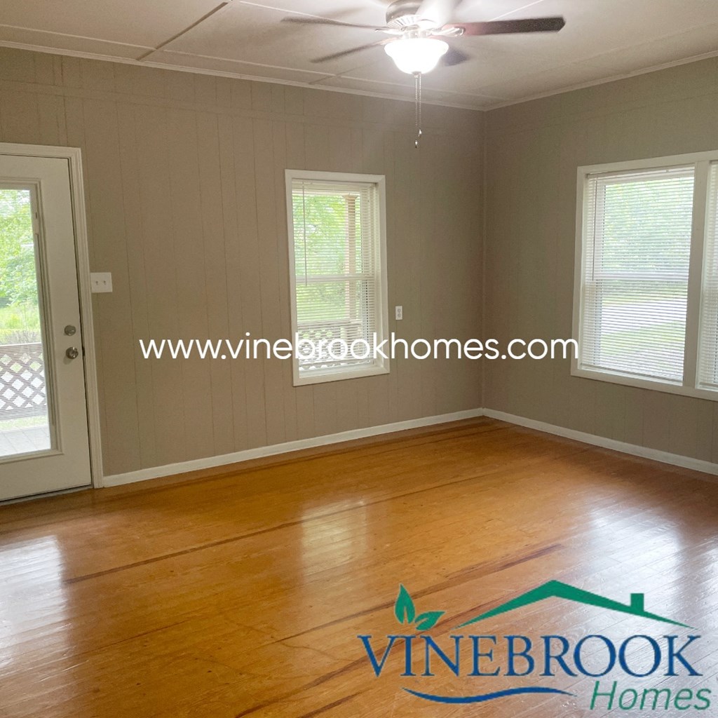 an empty living room with wood floors and a ceiling fan