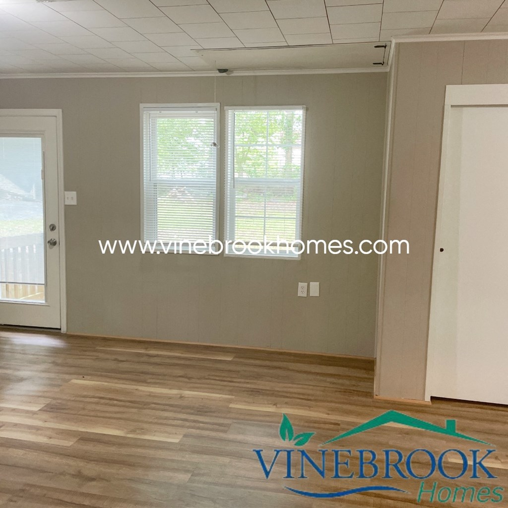 a living room with a hard wood floor and two windows