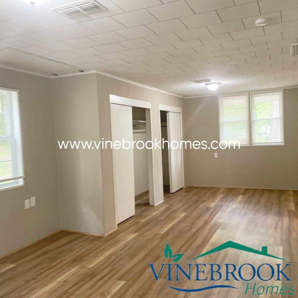 an empty living room with a hard wood floor and white walls