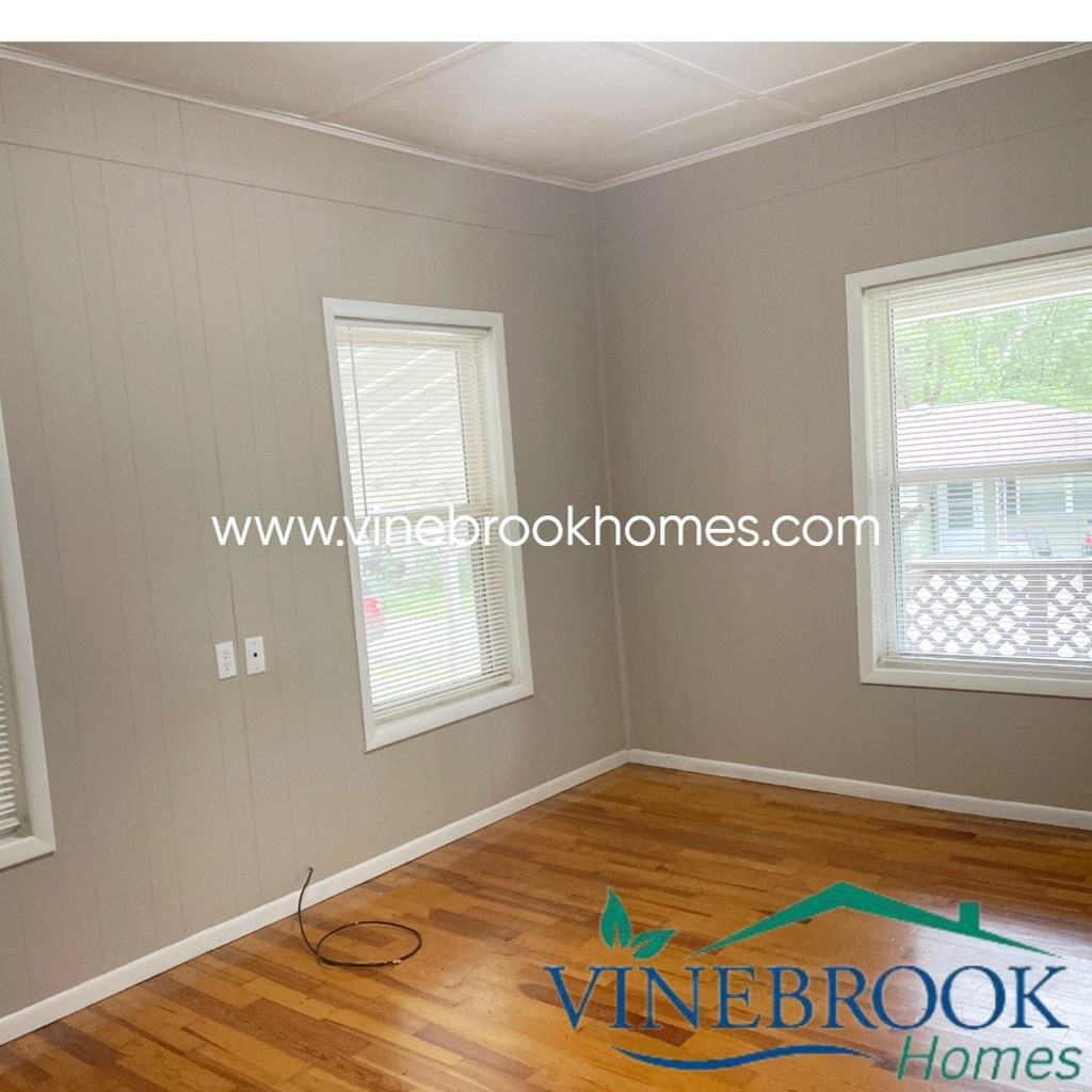 a room with a hard wood floor and two windows