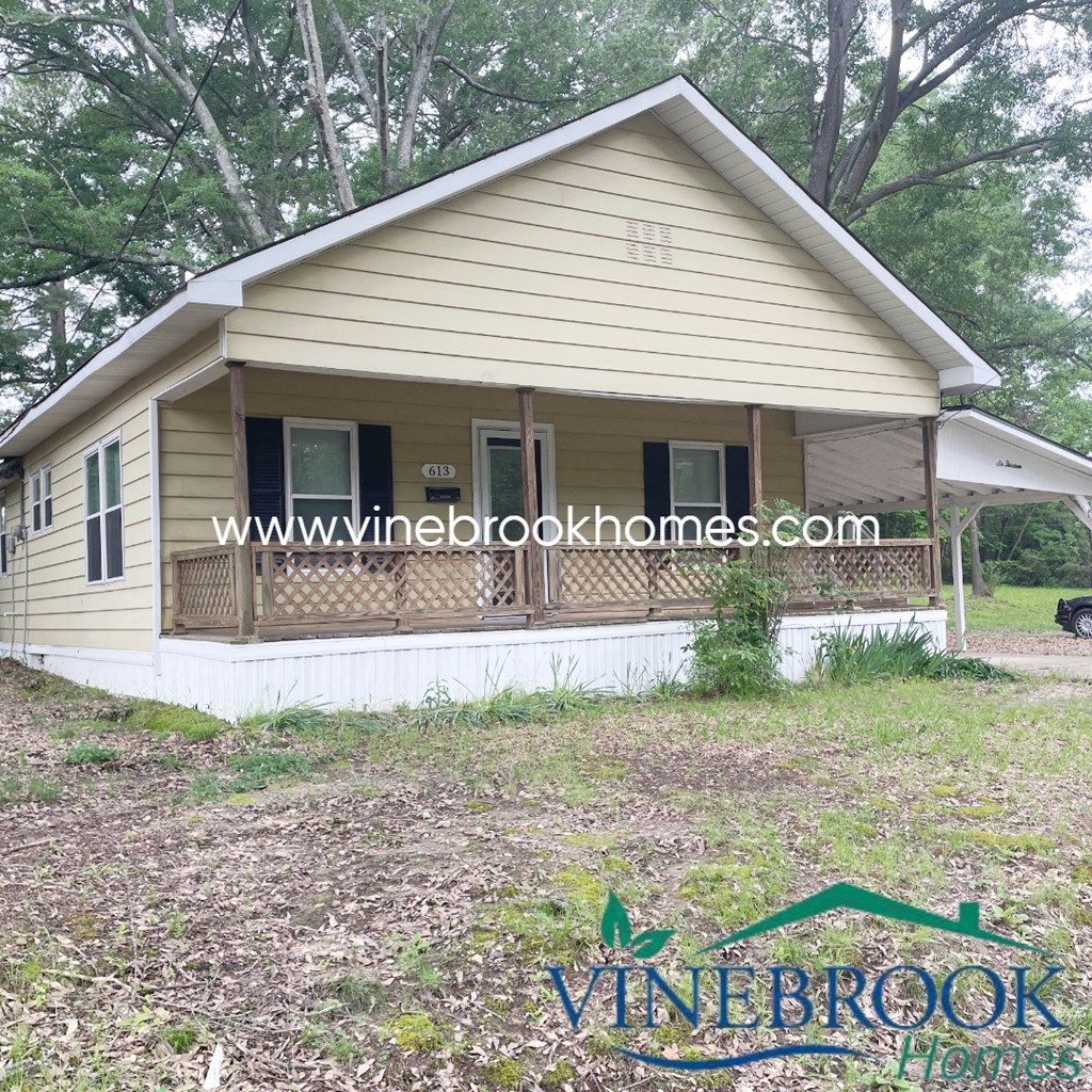 a small house with a porch and a yard with trees