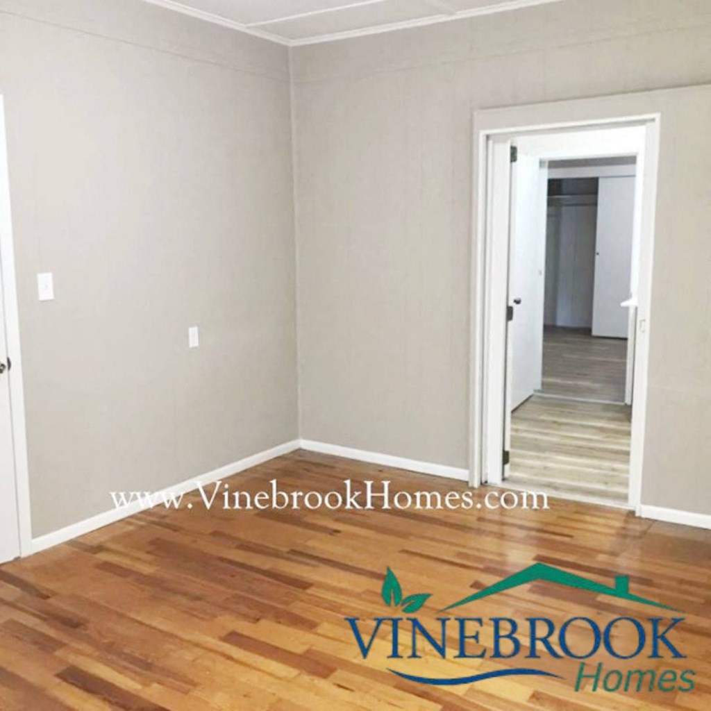a living room with a hard wood floor and a door to a hallway
