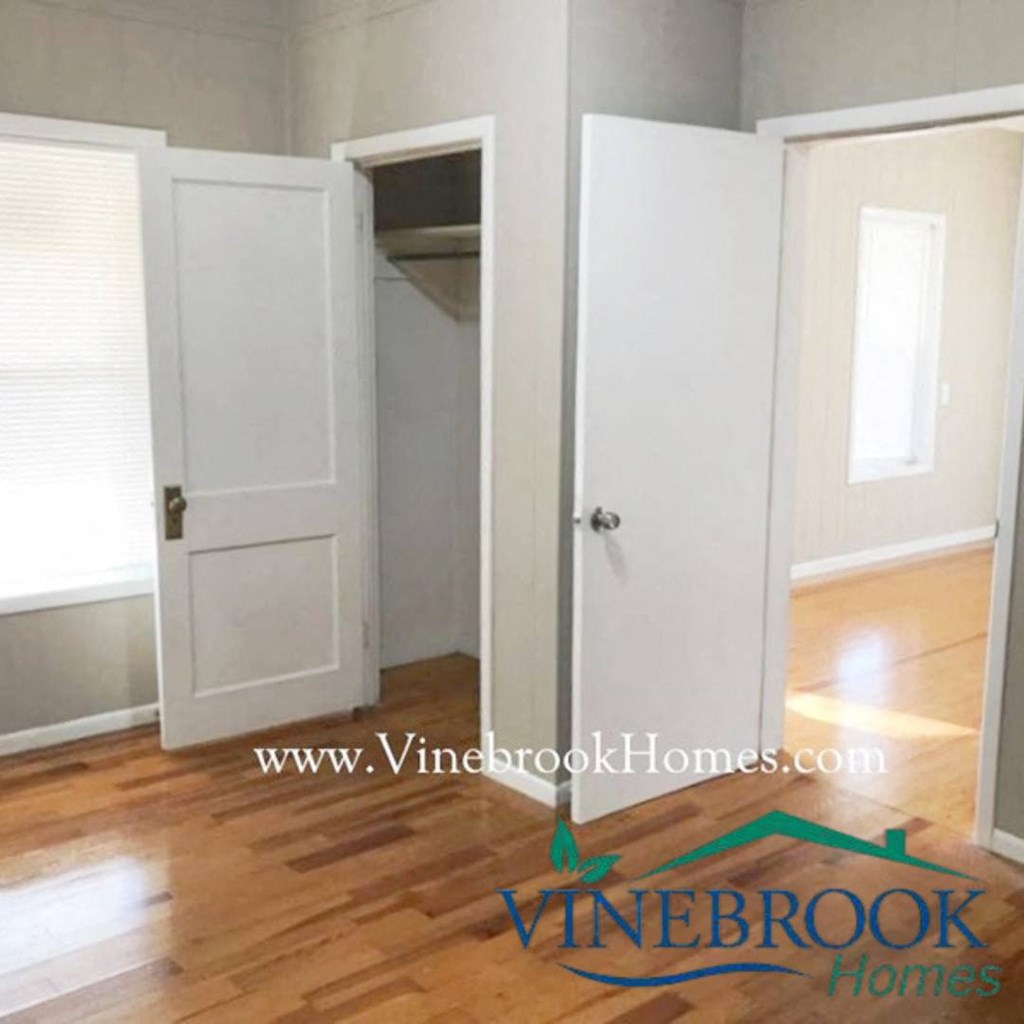 an empty room with white doors and a hard wood floor
