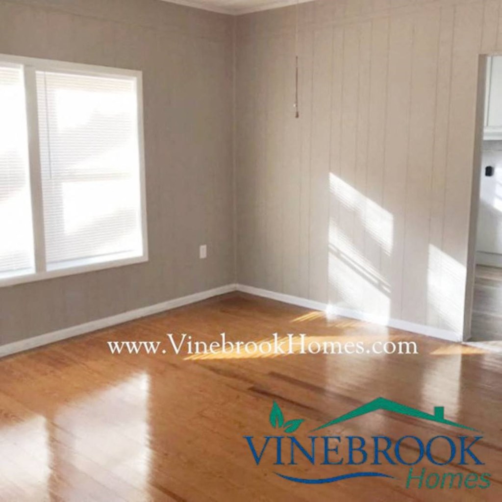 a living room with a hard wood floor and white walls